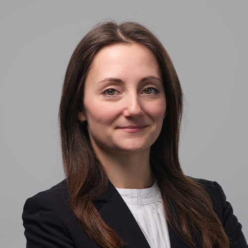 Porträt von Nicola Kocakova vor neutralem Hintergrund, frontal aufgenommen.