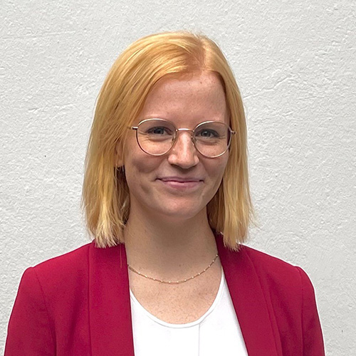 Porträt von Nina Schwaiger vor neutralem Hintergrund, frontal aufgenommen.